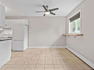 This bright and airy dining area features a convenient built-in shelf beneath the window, perfect for plants or decor.