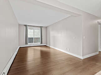 Discover this bright and airy living space, featuring gleaming hardwood floors that reflect the natural light pouring in from the large window.