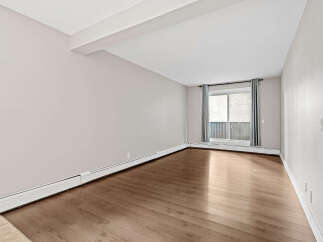 Experience modern living in this spacious room featuring elegant hardwood floors and a neutral color palette, perfect for any decor style.
