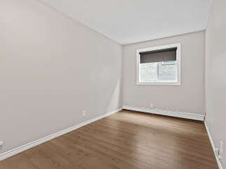 This empty room features light grey walls and a textured ceiling, creating a neutral and versatile space.