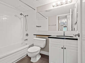 This bathroom features a pristine white bathtub and shower combination, perfect for relaxing soaks or quick rinses.