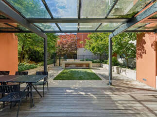 Enjoy outdoor living in this modern backyard featuring a sleek dining set on a wooden deck, perfect for al fresco meals.