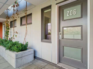 Discover modern living with this stylish entrance featuring a sleek gray door with frosted glass panels and the unit number '206' prominently displayed.