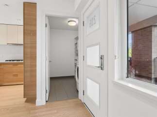 Step into a modern and inviting entryway featuring sleek wooden cabinetry and a bright, open kitchen space.