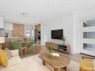Experience modern living in this beautifully staged open-concept space, featuring a sleek kitchen with wood cabinetry and stainless steel appliances.