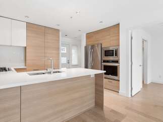 Experience modern living in this stunning kitchen featuring sleek white countertops and a waterfall island.