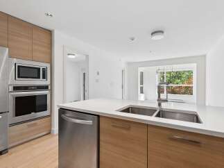Experience modern living in this stunning kitchen featuring sleek stainless steel appliances, including a built-in microwave and oven, complemented by warm wood cabinetry.