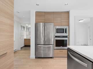 Experience modern living in this sleek kitchen featuring stainless steel appliances, including a French door refrigerator, built-in microwave, and oven.
