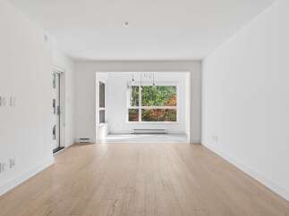 Step into this bright and airy living space, featuring gleaming hardwood floors and abundant natural light pouring in from large windows.
