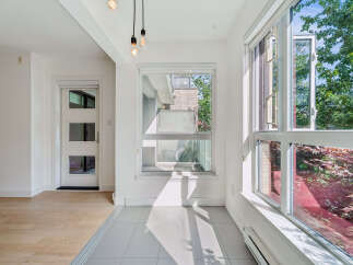 Bright and airy sunroom with large windows offering views of lush greenery.