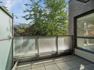 Enjoy the outdoors on this modern balcony featuring frosted glass railings for privacy and a sleek metal frame.