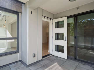 Step into this modern apartment featuring a spacious balcony with a sliding glass door and a charming white entry door with three glass panels.