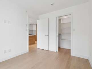 Step into this bright and airy living space, featuring pristine white walls and elegant light wood flooring.