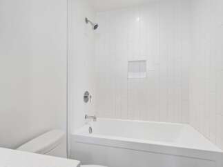 Experience modern comfort in this pristine white bathroom, featuring a sleek bathtub and shower combination.