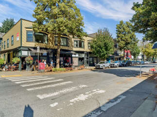 Discover this prime commercial corner property, featuring a vibrant street-level cafe with outdoor seating and upper-level residential units.