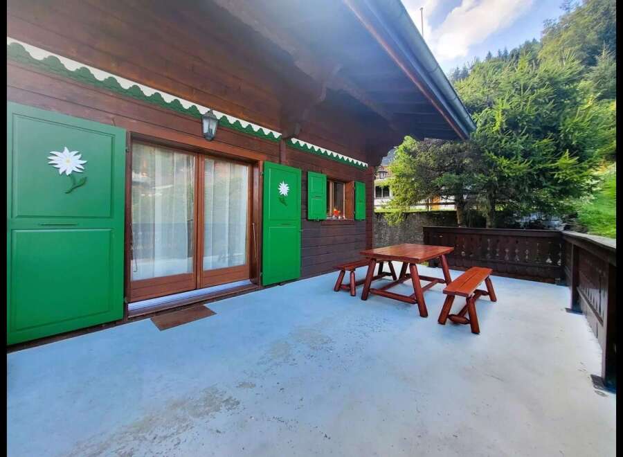 Enjoy the outdoors on this charming wooden cabin's spacious patio, complete with a rustic picnic table and benches.