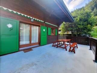 Enjoy the outdoors on this charming wooden cabin's spacious patio, complete with a rustic picnic table and benches.