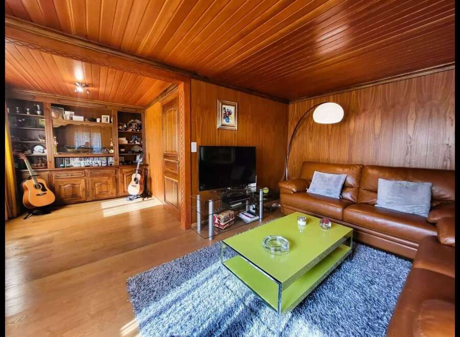 This cozy living room features warm wood paneling on the walls and ceiling, creating a rustic and inviting atmosphere.