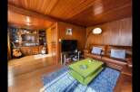 This cozy living room features warm wood paneling on the walls and ceiling, creating a rustic and inviting atmosphere.