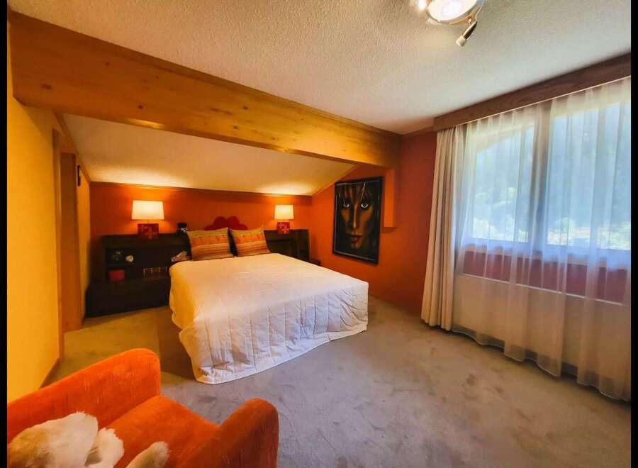 This charming bedroom features a cozy queen-size bed with a white quilted comforter, complemented by two decorative pillows.