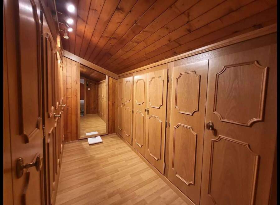 Step into this charming wooden hallway, featuring ample built-in wardrobes with elegant detailing perfect for storage.