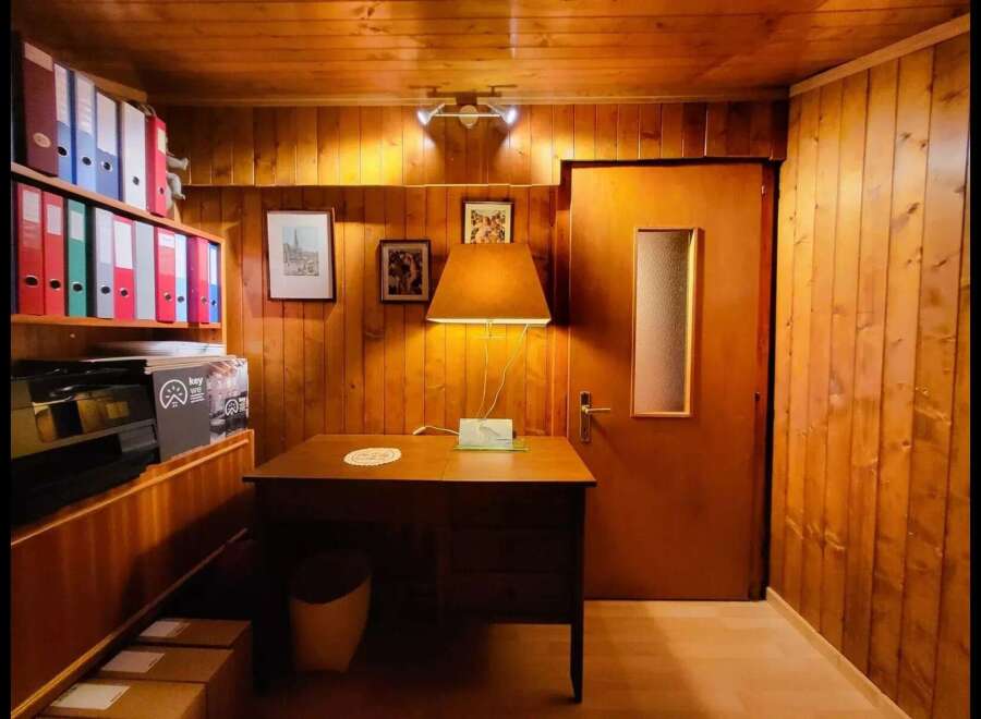 Discover this charming office space featuring warm wood-paneled walls and a cozy desk area, perfect for focused work.