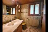 This charming bathroom features a spacious vanity with a marble countertop and a modern faucet, complemented by a large mirror reflecting the wooden ceiling.