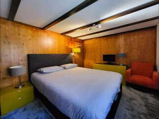 Experience cozy comfort in this charming bedroom, featuring warm wood-paneled walls and exposed beam ceilings.