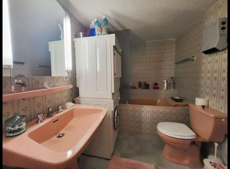 This charming bathroom features a large pink sink and a matching toilet, creating a cohesive and retro aesthetic.