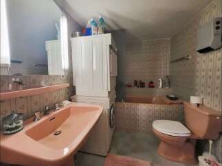 This charming bathroom features a large pink sink and a matching toilet, creating a cohesive and retro aesthetic.