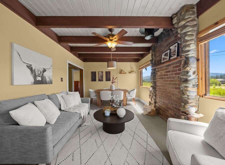 Experience rustic charm in this inviting living space featuring a striking stone and brick fireplace, complemented by exposed wooden beams on the vaulted ceiling.