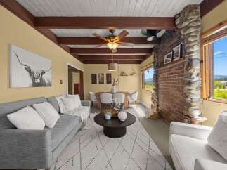 Experience rustic charm in this inviting living space featuring a striking stone and brick fireplace, complemented by exposed wooden beams on the vaulted ceiling.