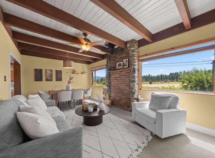 Experience breathtaking views from this charming living and dining area, featuring a rustic stone fireplace and exposed wooden beams.