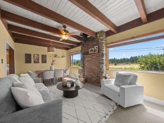 Experience breathtaking views from this charming living and dining area, featuring a rustic stone fireplace and exposed wooden beams.