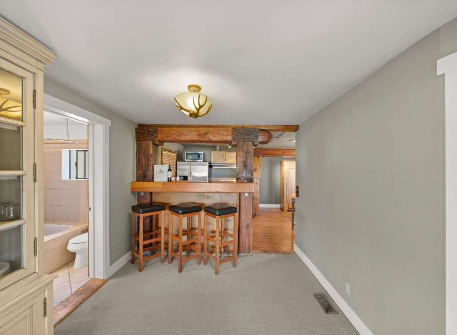 Step into a charming space featuring a rustic wooden beam bar with three stools, perfect for casual dining or entertaining.
