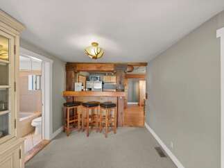 Step into a charming space featuring a rustic wooden beam bar with three stools, perfect for casual dining or entertaining.
