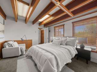Discover this charming bedroom featuring a cozy queen-size bed adorned with plush white bedding and a textured throw.