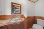This charming bathroom features a classic white sink set against a warm wooden vanity and tiled countertop.