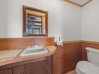 This charming bathroom features a classic white sink set against a warm wooden vanity and tiled countertop.