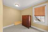 This bedroom features a warm and inviting atmosphere with its soft yellow walls and neutral carpeting.