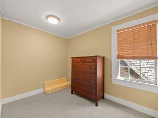 This bedroom features a warm and inviting atmosphere with its soft yellow walls and neutral carpeting.