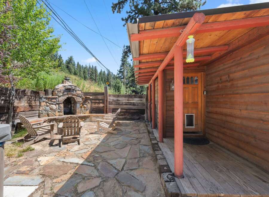 Enjoy outdoor living with this charming patio featuring a stone fireplace and comfortable Adirondack chairs, perfect for cozy evenings.