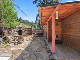 Enjoy outdoor living with this charming patio featuring a stone fireplace and comfortable Adirondack chairs, perfect for cozy evenings.