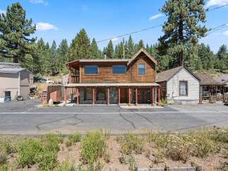 Discover this charming rustic property featuring a two-story wooden building with a covered porch and stone accents on the lower level.