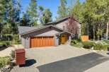 Discover this charming home featuring a warm and inviting ambiance, highlighted by a beautiful wooden garage door and a bright yellow front door.