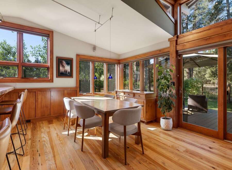 Experience seamless indoor-outdoor living in this stunning dining area, featuring expansive windows that flood the space with natural light and offer picturesque views of the surrounding trees.