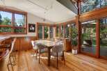 Experience seamless indoor-outdoor living in this stunning dining area, featuring expansive windows that flood the space with natural light and offer picturesque views of the surrounding trees.