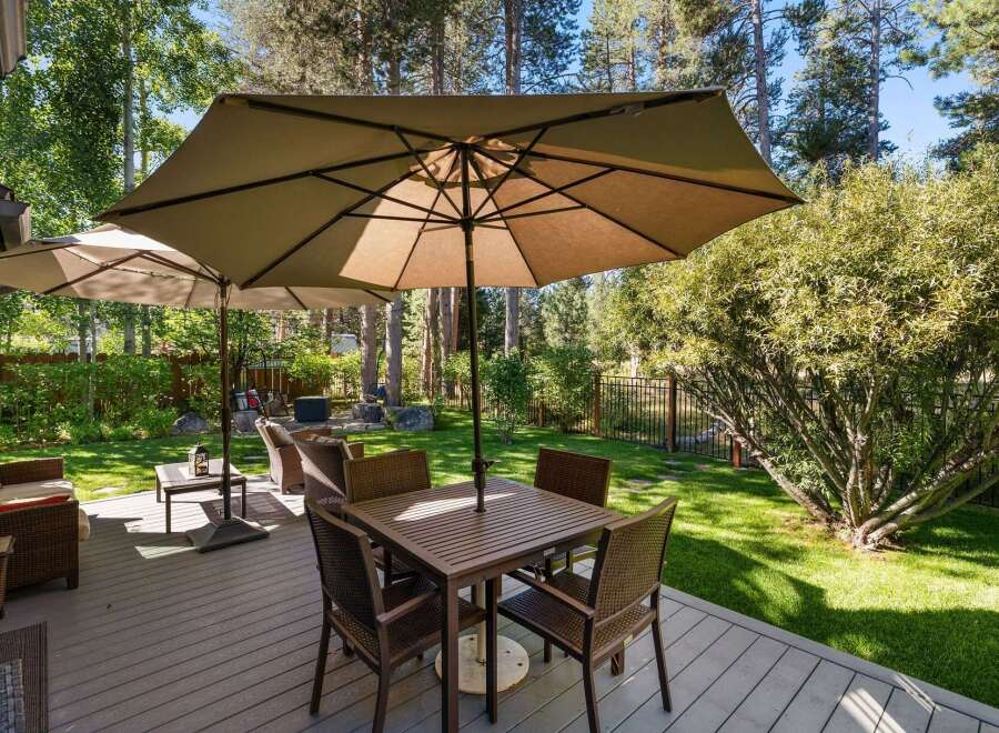 Enjoy outdoor living at its finest on this spacious deck, complete with a dining set under a large umbrella and comfortable seating areas.