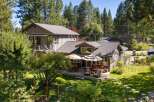 This charming home offers a spacious deck perfect for outdoor entertaining, complete with comfortable seating and dining areas under umbrellas.