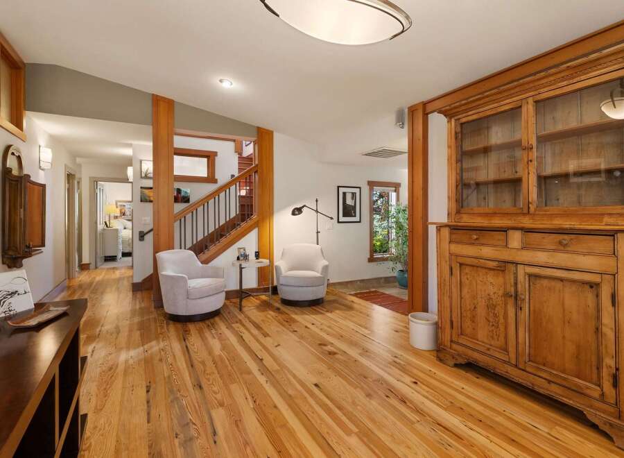 Step into a warm and inviting living space featuring beautiful natural wood floors and a charming rustic hutch.